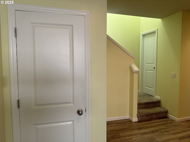 corridor featuring wood finished floors, baseboards, and stairs