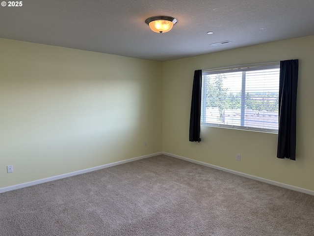 carpeted spare room featuring a textured ceiling and baseboards