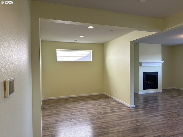 below grade area with wood finished floors, baseboards, recessed lighting, and a fireplace