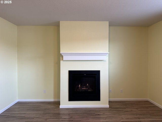 unfurnished living room featuring wood finished floors, a fireplace, and baseboards