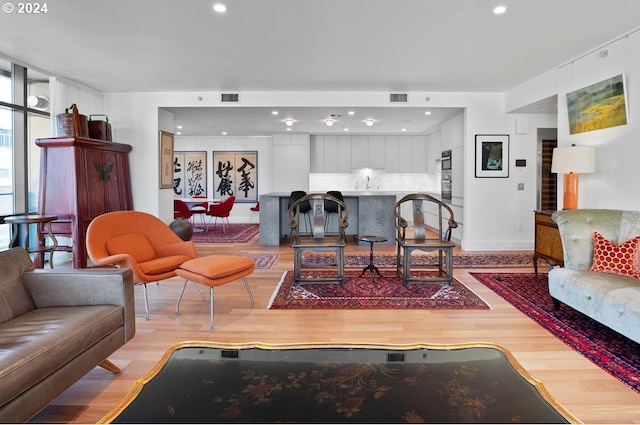 living area featuring recessed lighting, light wood finished floors, and visible vents