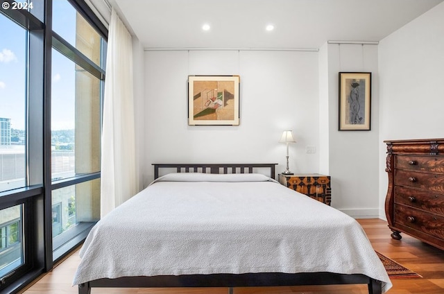 bedroom featuring recessed lighting, wood finished floors, and a wall of windows