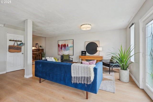 living room with light wood finished floors, baseboards, and healthy amount of natural light