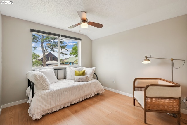 bedroom featuring light wood-style floors, baseboards, ceiling fan, and a textured ceiling