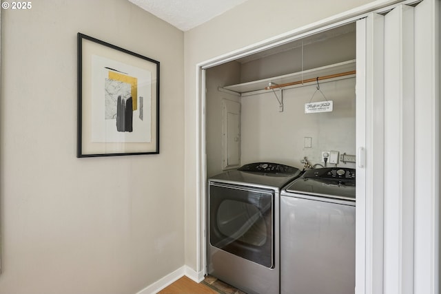 laundry area featuring washer and dryer, baseboards, and wood finished floors
