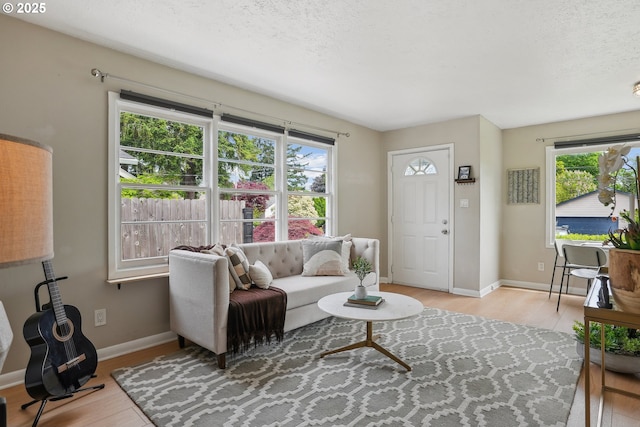 living room with light wood-type flooring, baseboards, and a textured ceiling