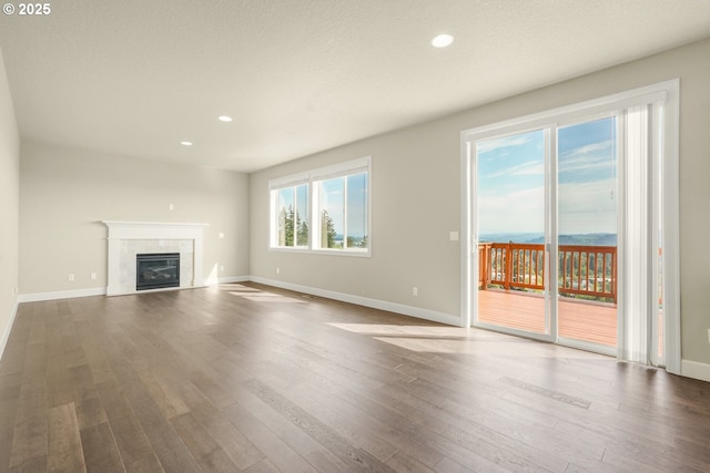 unfurnished living room with recessed lighting, baseboards, a tiled fireplace, and wood finished floors