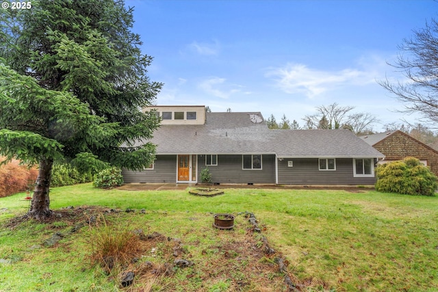 rear view of house with a lawn and an outdoor fire pit