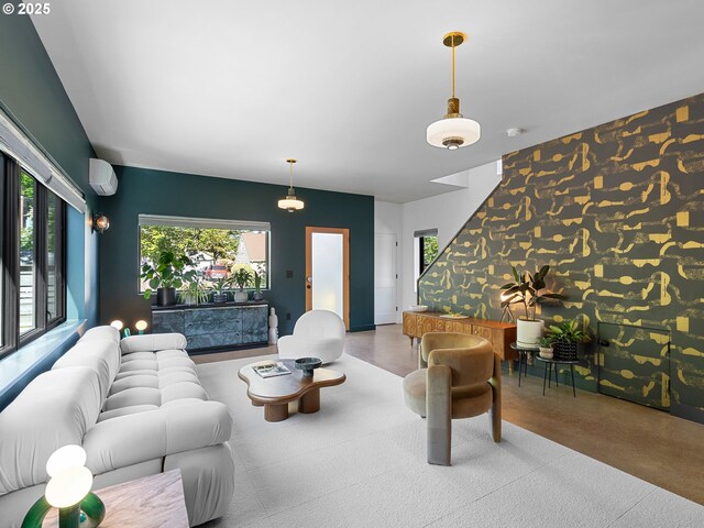 living area featuring an accent wall, a wall mounted air conditioner, and wallpapered walls