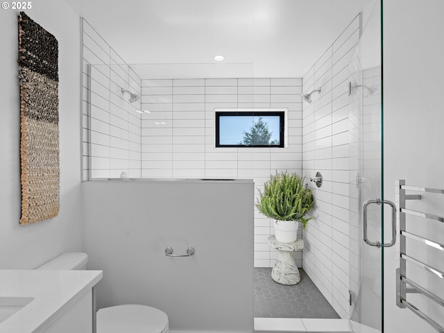 bathroom with a tile shower, toilet, vanity, and recessed lighting