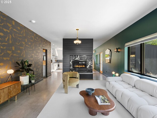 living area with wallpapered walls, a premium fireplace, concrete flooring, and baseboards