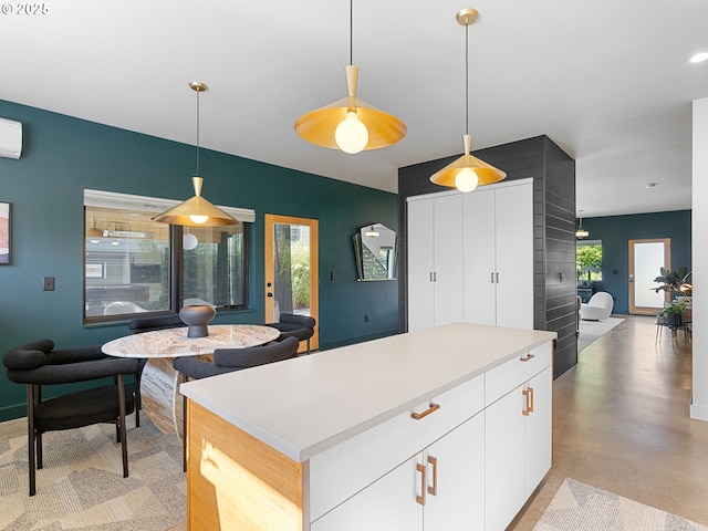 kitchen with white cabinets, pendant lighting, light countertops, a center island, and open floor plan