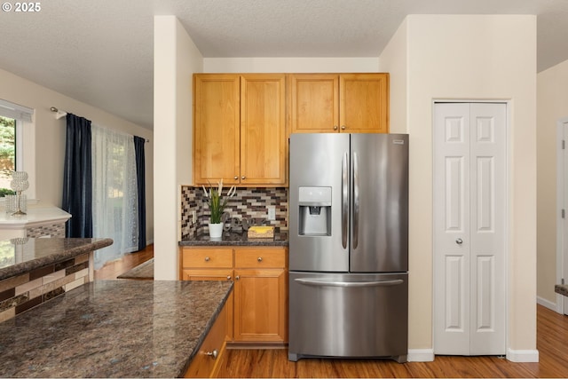 4540 SW 11th St, Gresham, OR 97080 - kitchen featuring stainless steel fridge, dark stone counters, backsplash, light wood-style flooring, and brown cabinetry