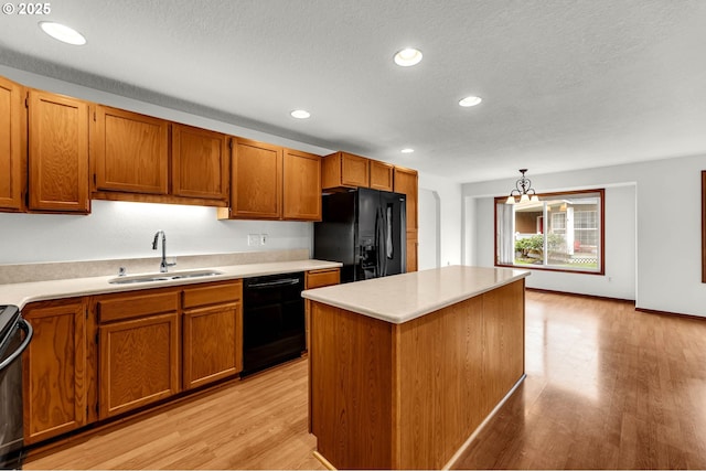 kitchen with black appliances, light wood-type flooring, brown cabinets, and a sink