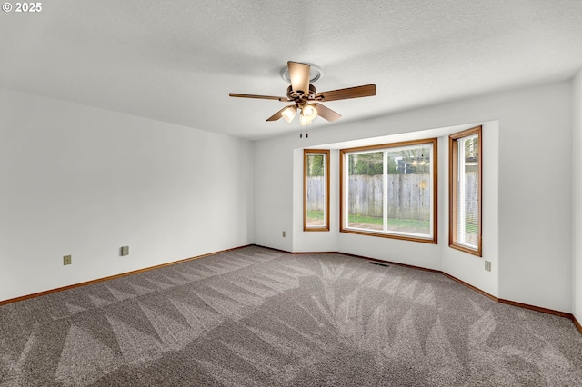 empty room featuring visible vents, a textured ceiling, carpet, baseboards, and ceiling fan