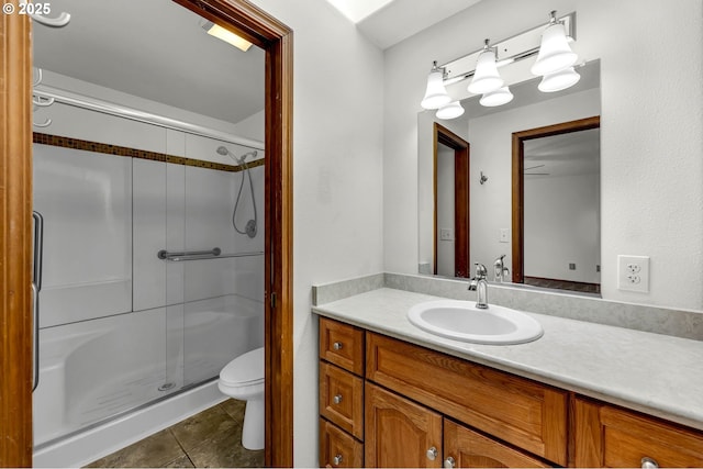 bathroom with tile patterned floors, a shower stall, toilet, and vanity