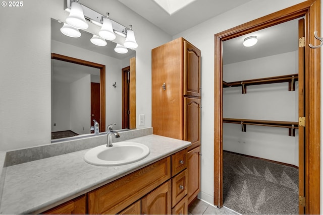 bathroom featuring a spacious closet, a skylight, vanity, and baseboards