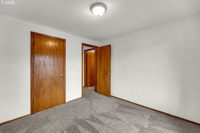 unfurnished bedroom featuring baseboards, a closet, carpet floors, and a textured ceiling