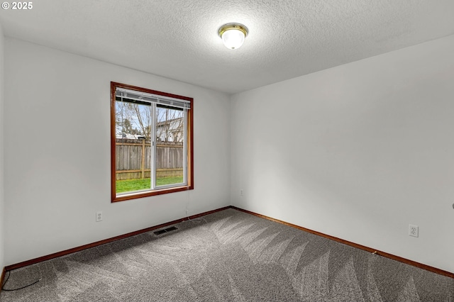 carpeted empty room with baseboards, visible vents, and a textured ceiling