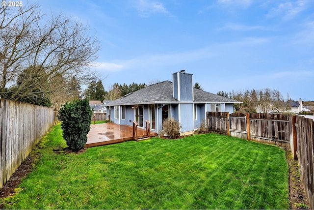 back of property featuring a deck, a fenced backyard, a yard, a shingled roof, and a chimney