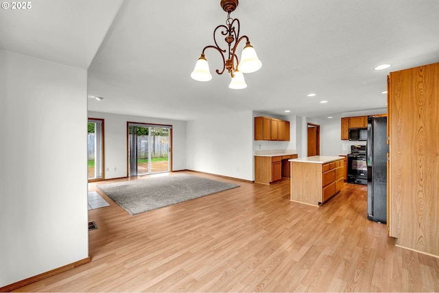 kitchen featuring a kitchen island, black appliances, light countertops, open floor plan, and light wood-type flooring