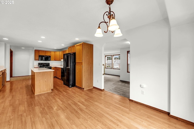 kitchen with light wood finished floors, light countertops, arched walkways, a notable chandelier, and black appliances