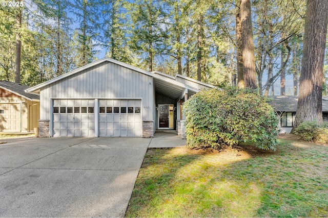 mid-century inspired home featuring stone siding, concrete driveway, an attached garage, and a front yard