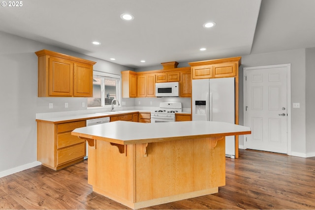 kitchen featuring dark wood finished floors, white appliances, recessed lighting, and a kitchen bar