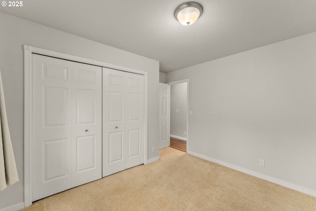 unfurnished bedroom with carpet, baseboards, a closet, and a textured ceiling