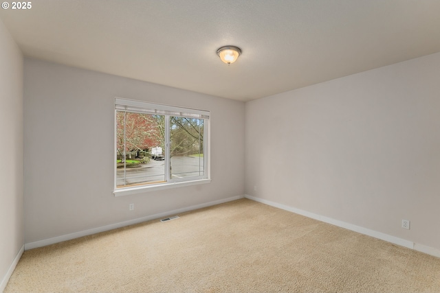 unfurnished room featuring carpet, visible vents, and baseboards