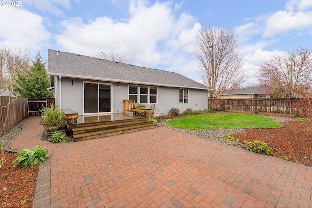 rear view of property with a yard, a patio, a shingled roof, and a fenced backyard