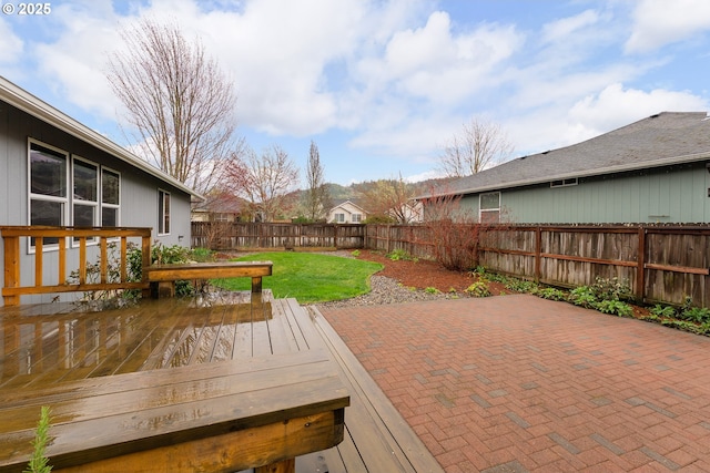 wooden terrace featuring a yard, a fenced backyard, and a patio area