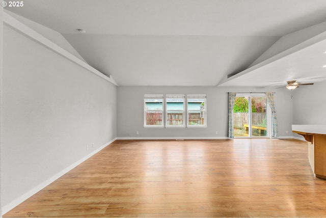 unfurnished living room with ceiling fan, baseboards, lofted ceiling, and light wood-style flooring