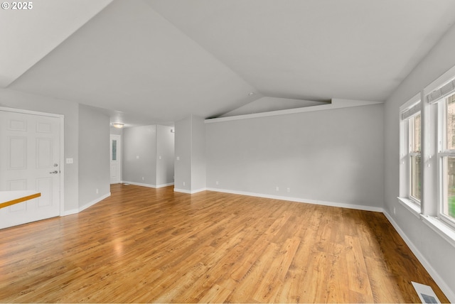 unfurnished living room featuring visible vents, light wood-style flooring, baseboards, and vaulted ceiling