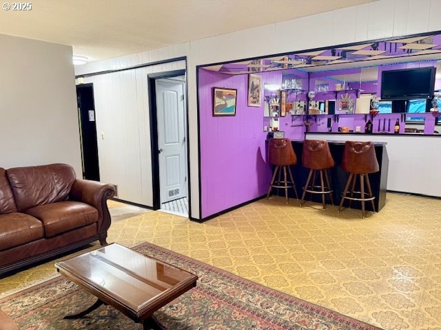 living room featuring wood walls and indoor bar