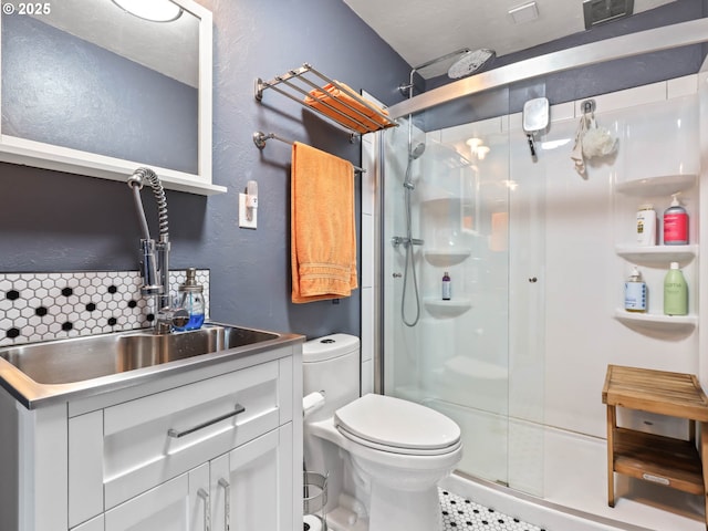 bathroom featuring backsplash, tile patterned floors, toilet, vanity, and a shower with shower door