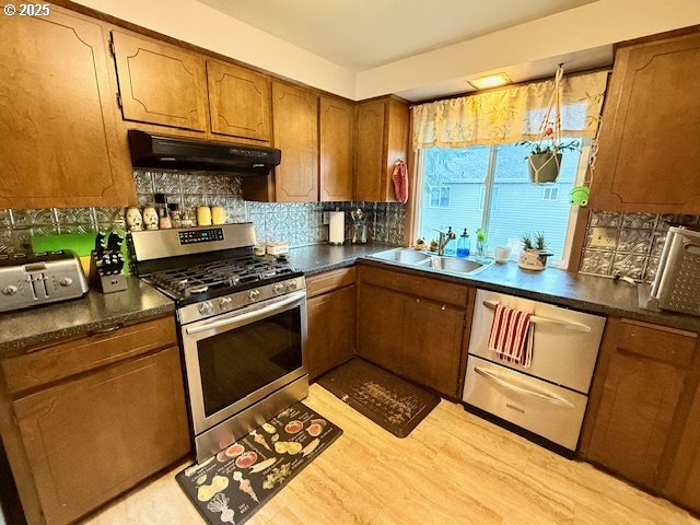 kitchen with backsplash, stainless steel appliances, light hardwood / wood-style floors, and sink