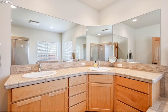 full bathroom with double vanity, a stall shower, a sink, and recessed lighting