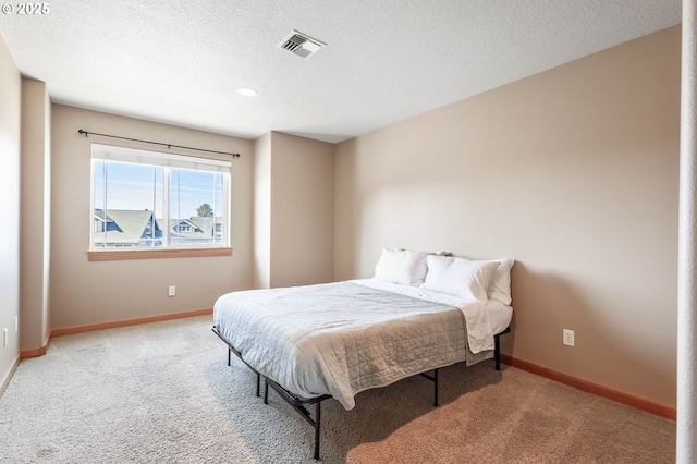 carpeted bedroom featuring baseboards, visible vents, and a textured ceiling