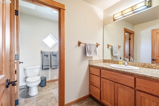 bathroom with toilet, tile patterned floors, baseboards, and vanity