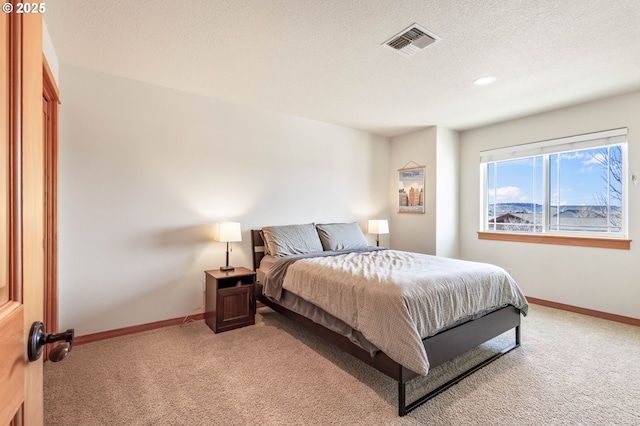 bedroom with visible vents, light carpet, baseboards, and a textured ceiling