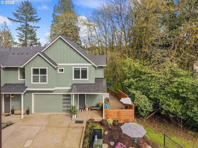 view of front of home with roof with shingles, fence, board and batten siding, and concrete driveway