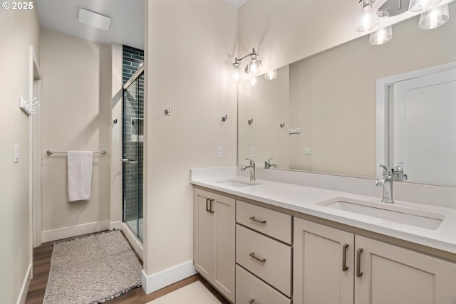 bathroom with wood finished floors, baseboards, a sink, and a stall shower