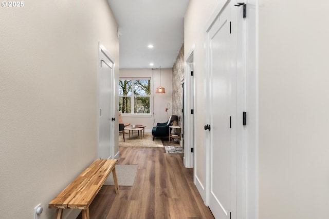 hall featuring baseboards, recessed lighting, and wood finished floors