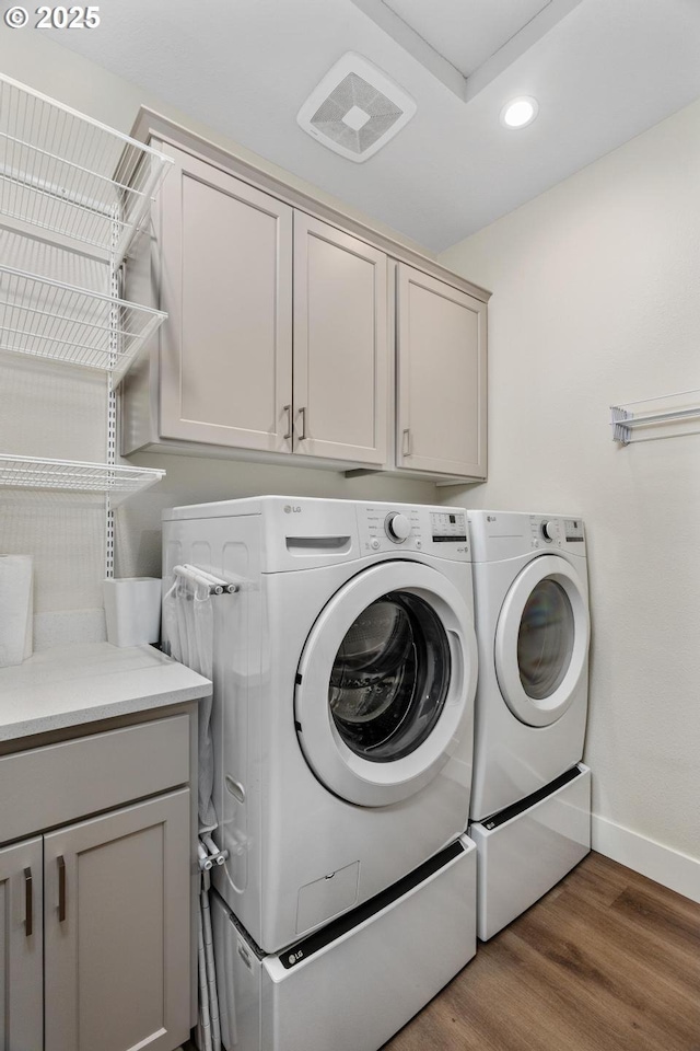 laundry area featuring wood finished floors, baseboards, recessed lighting, separate washer and dryer, and cabinet space