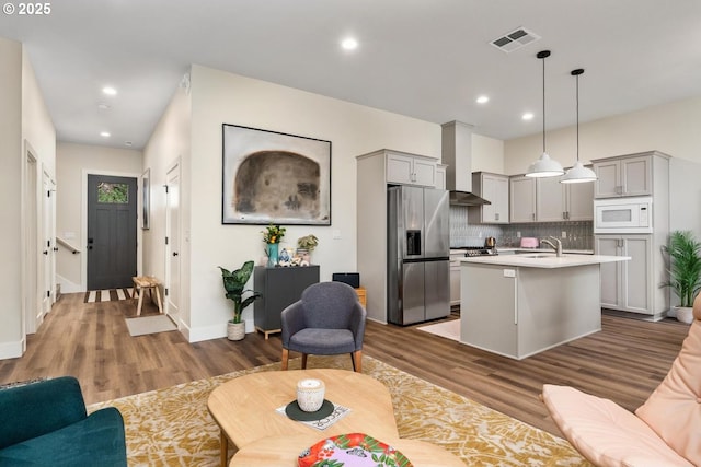 living area with recessed lighting, baseboards, visible vents, and wood finished floors