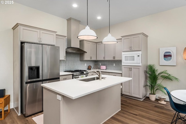 kitchen with wall chimney exhaust hood, tasteful backsplash, a sink, dark wood finished floors, and appliances with stainless steel finishes