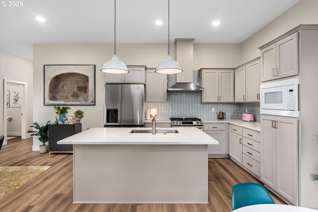 kitchen featuring wall chimney range hood, gray cabinets, stainless steel appliances, and a sink