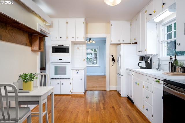 1856 SE Saint Andrews Dr, Portland, OR 97202 - kitchen with a sink, light wood-style flooring, white cabinetry, light countertops, and white appliances