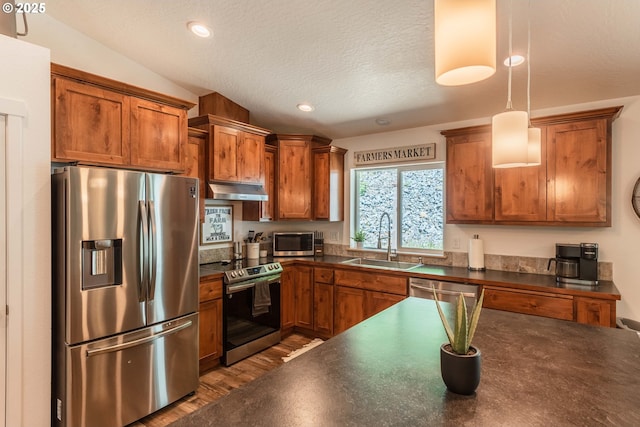 kitchen with brown cabinetry, dark countertops, a sink, and stainless steel appliances